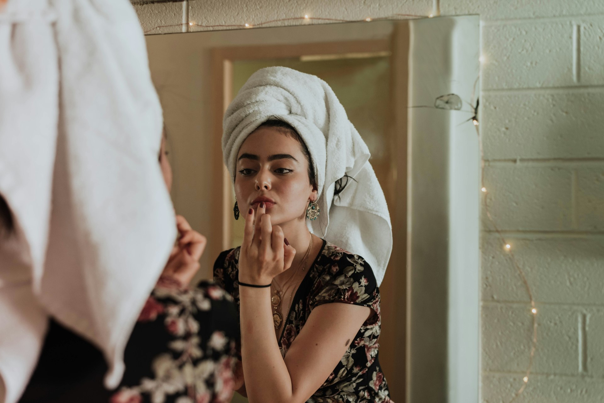 Mulher com toalha no cabelo, se olhando no espelho depois do banho